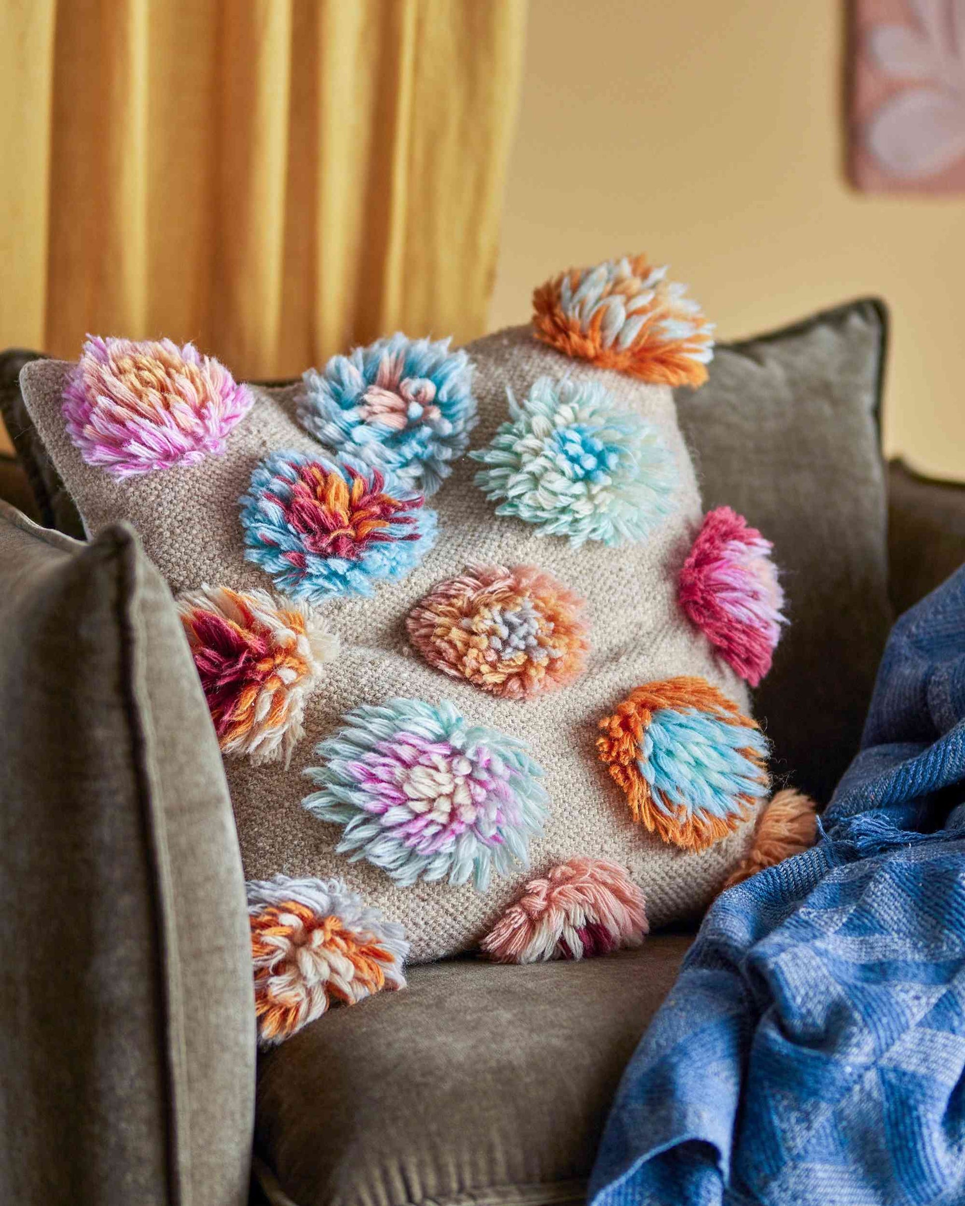 Kissen mit bunten Wollblumen.