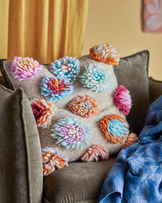 Kissen mit bunten Wollblumen.